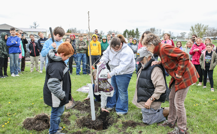 Tom and Kathy Dean, who donated the tree, along with friends and family of Reba Carothers, plant a bur oak at the south end of the playground.